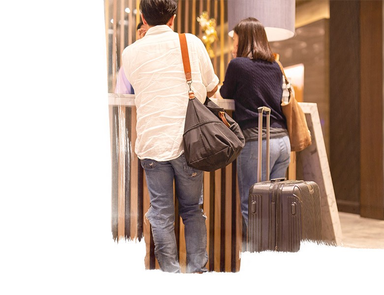 Asian couple with suitcase checking in at hotel reception